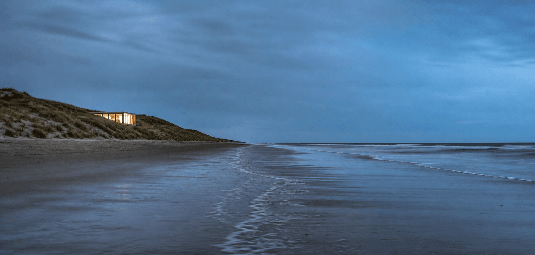 Interprétation visuelle d’une plage au crépuscule, avec une lumière dans les dunes.